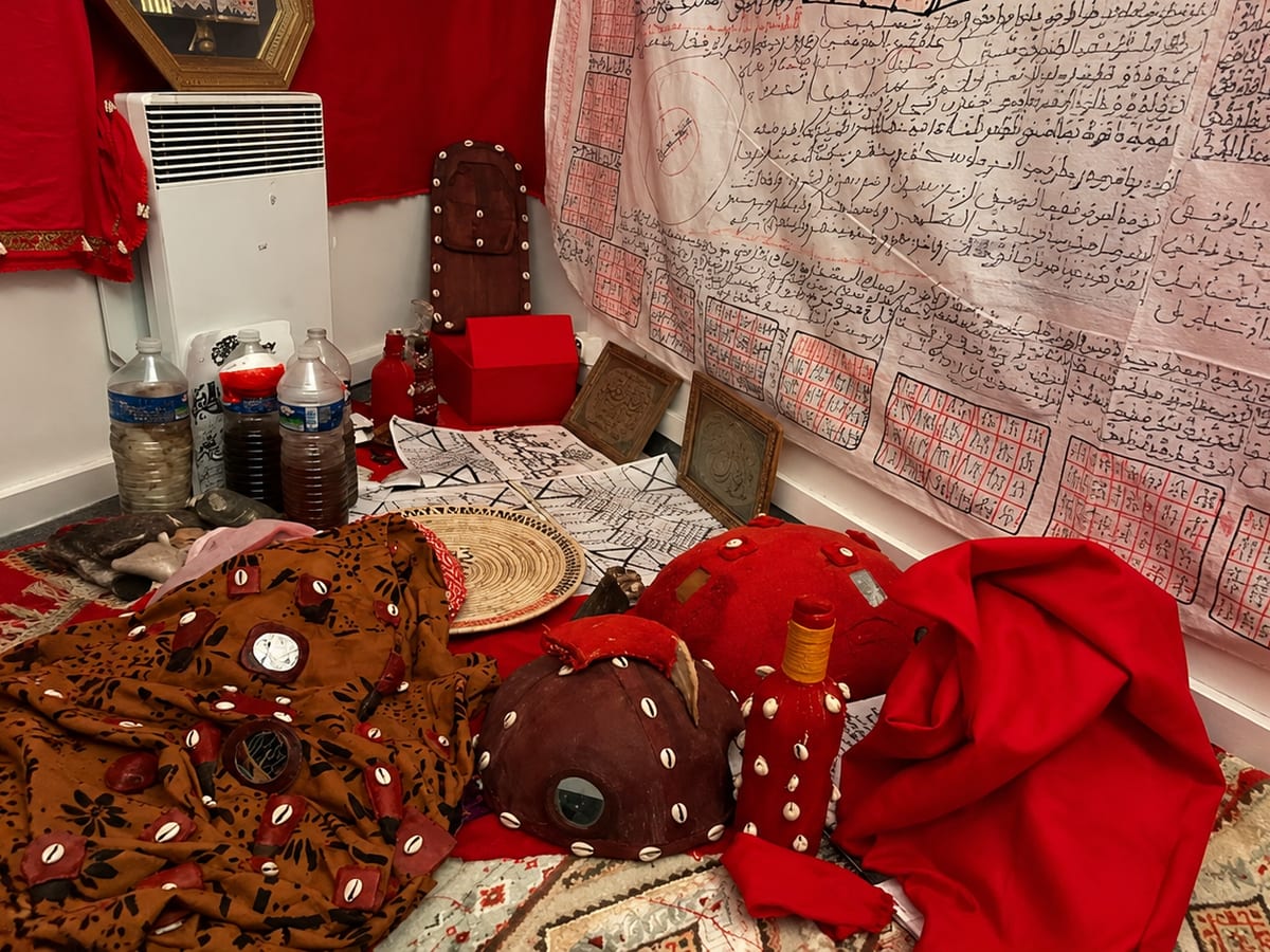 Étoffes rouges, objets rituels en cauris et manuscrit talismanique dans le cabinet